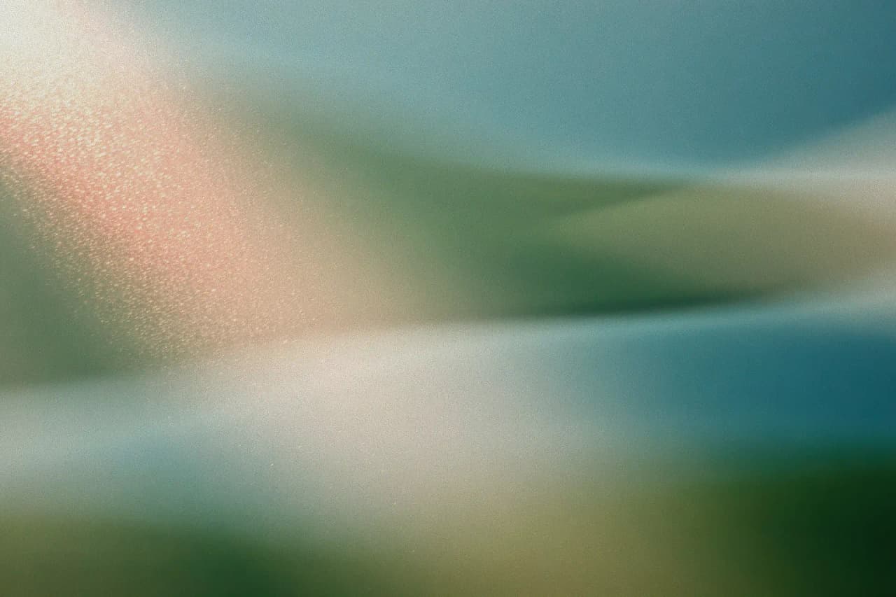 Grainy abstract landscape with pale blue water and soft green slopes